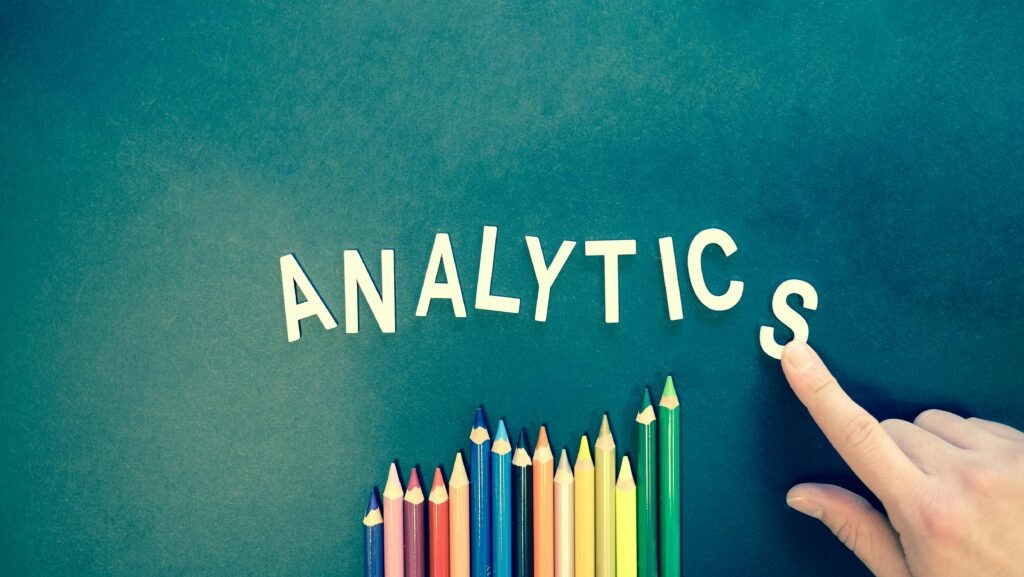 pexels-photo-185576-185576 Colored pencils and letters spelling 'ANALYTICS' on a textured background with a hand.