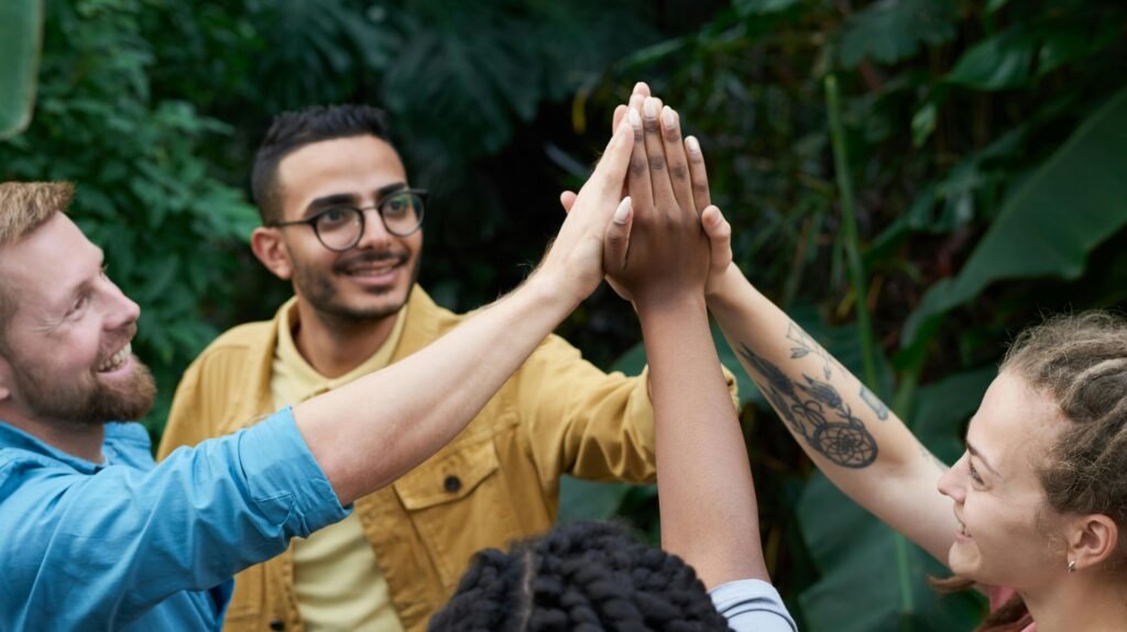 pexels-photo-3228685-3228685 A joyful group of friends high-fiving outdoors, symbolizing teamwork and camaraderie.
